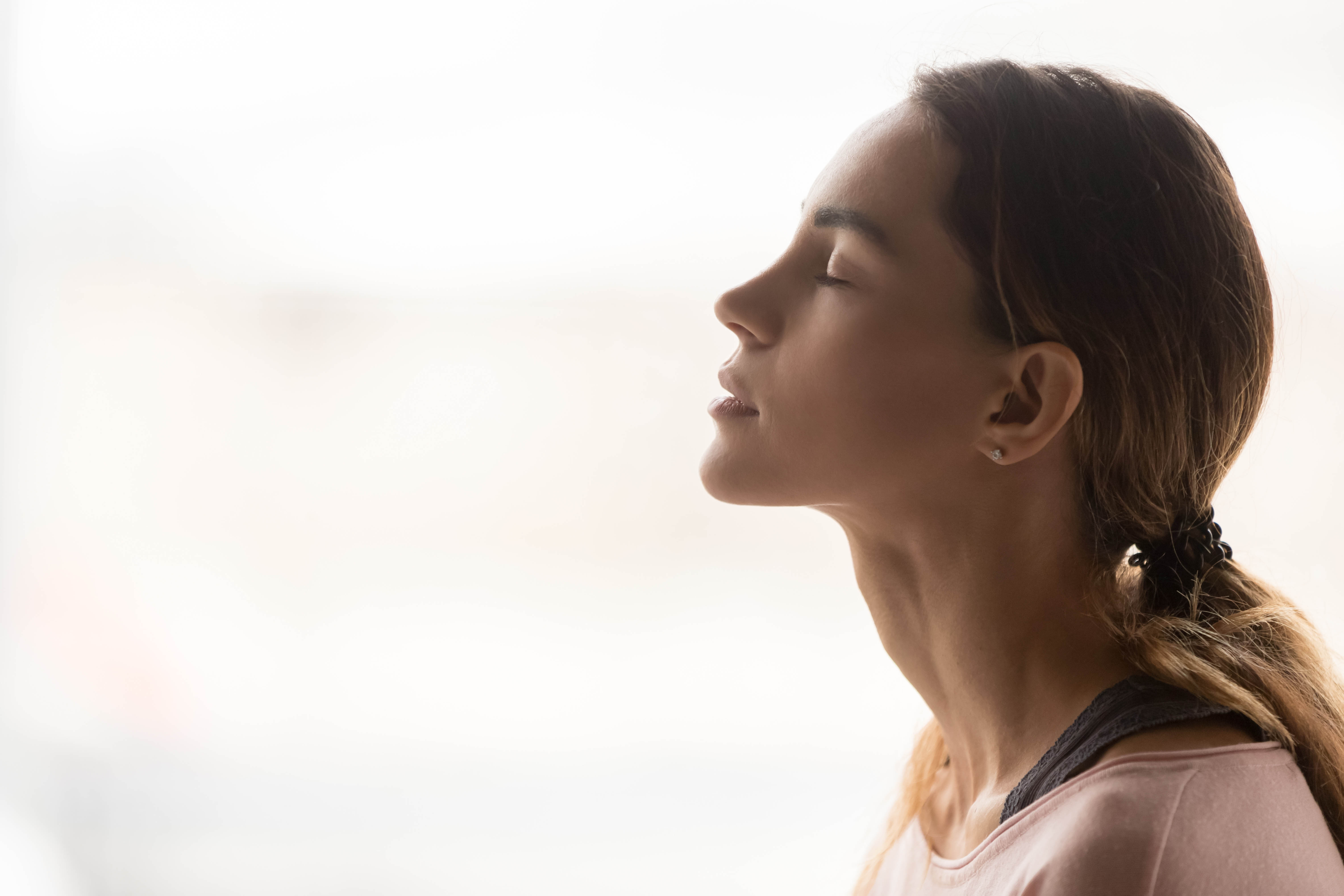 Young woman with her head tilted towards the sky. She has her eyes closed and is breathing deeply.